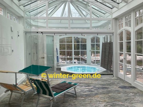 Orangerie Wintergarten mit Segmentbögen als Fitness- und Wellnessbereich, abgetrennt durch eine komplett verschiebbare Glaswand.
